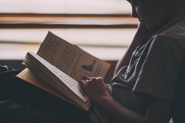 menino lendo livro terá menos risco de demência