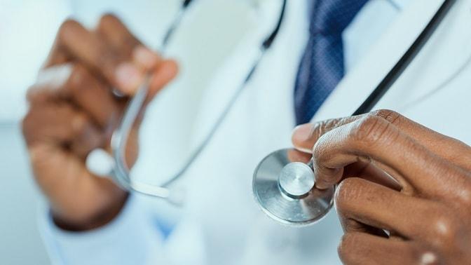médico segurando estetoscópio, mãos em foco