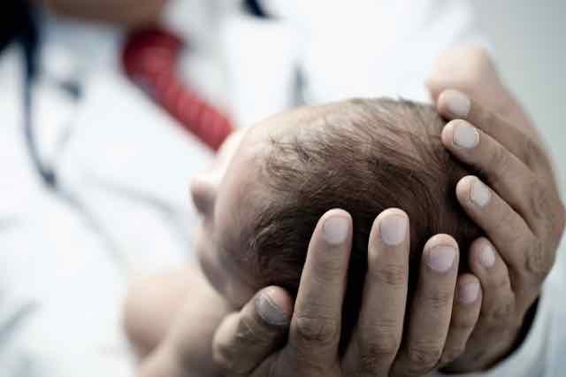 medico segurando um bebe nas mãos