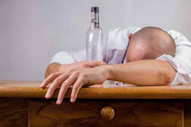 homem desmaiado com garrafa de vinho