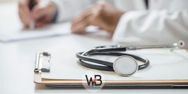 médico escrevendo em prancheta de paciente com pancreatite autoimune