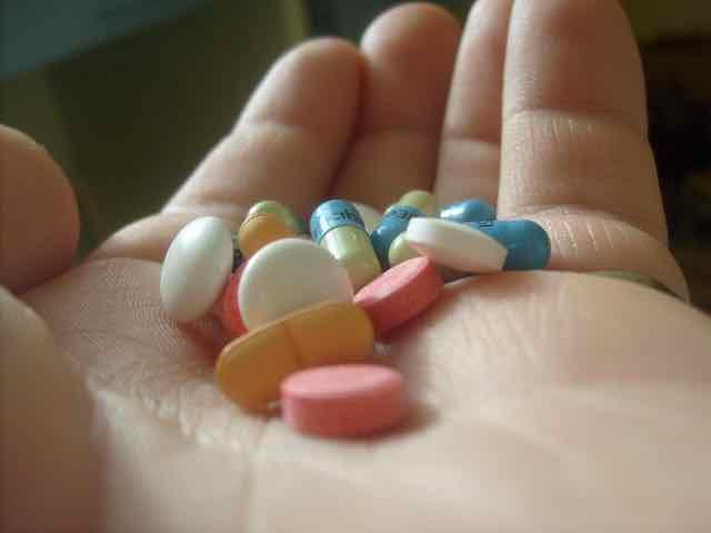 mão segurando vários medicamentos