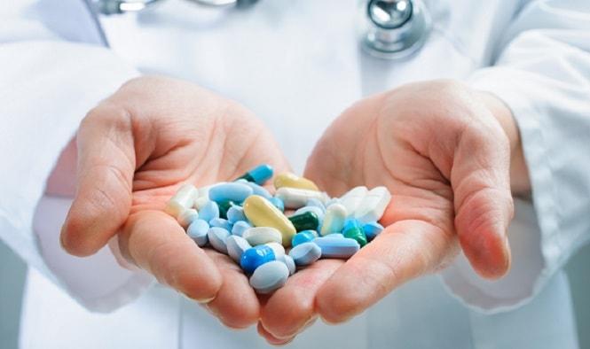 mãos de médico segurando vários medicamentos, como estatinas