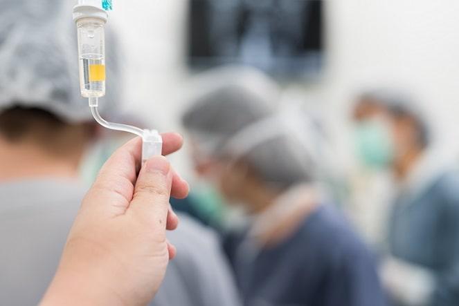 mão de enfermeiro regulando fluidos intravenosos em cirurgia com uso do ácido tranexâmico